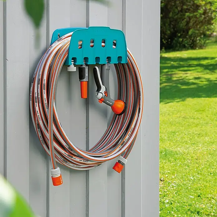 Gardena Wand-Schlauchhalterung - Kunststoff, Geeignet für: Wandmontage - Gartenschlauch auf einer aqua-türkisen Gardena Schlauchbox an einer Wand mit Schlauchanschlüssen und Gartenspritze.