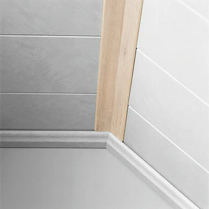 LOGOCLIC Faltleiste Eiche Colorado - 260 cm x 22 mm x 22 mm - Detailaufnahme von Sockelleisten, die den Übergang von Boden zu Wand in Grau- und Holztönen hervorheben. Perfekt für ein stilvolles Interieur.