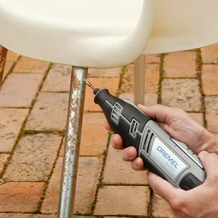 Dremel Drahtbürste Mod. 443 - Pinselkopf, Arbeitsdurchmesser: 3,2 mm - Ein Dremel 8200 Multifunktionswerkzeug wird zum Entfernen von Rost von einem Stuhlbein verwendet, was die Vielseitigkeit des Werkzeugs hervorhebt.
