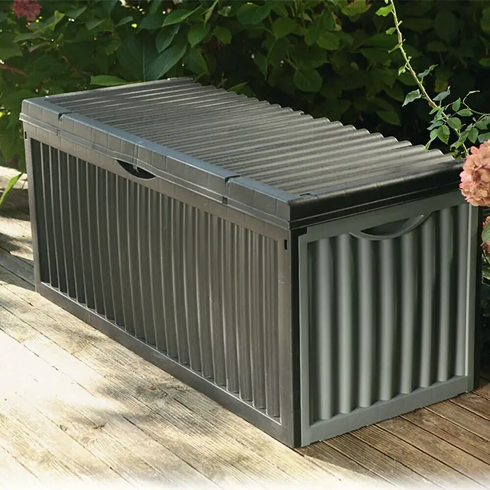 Jelenia Plast Garten-Aufbewahrungsbox Wave - 120 x 52 x 54 cm, Anthrazit, Kunststoff - Eine graue Gartenbox mit gerippter Textur auf einer Holzterrasse, umgeben von üppigem Grün. Praktische Aufbewahrungslösung für den Außenbereich.