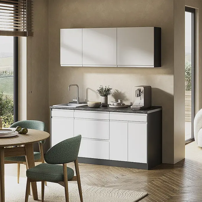Singleküche R-Line 160 cm Weiß Art.-Nr. 70559 -  - Eine moderne Kompaktküche mit weißen Ober- und Unterschränken, dunkler Arbeitsplatte und Sockel, integrierter Spüle und Kaffeemaschine, neben einem Essbereich.