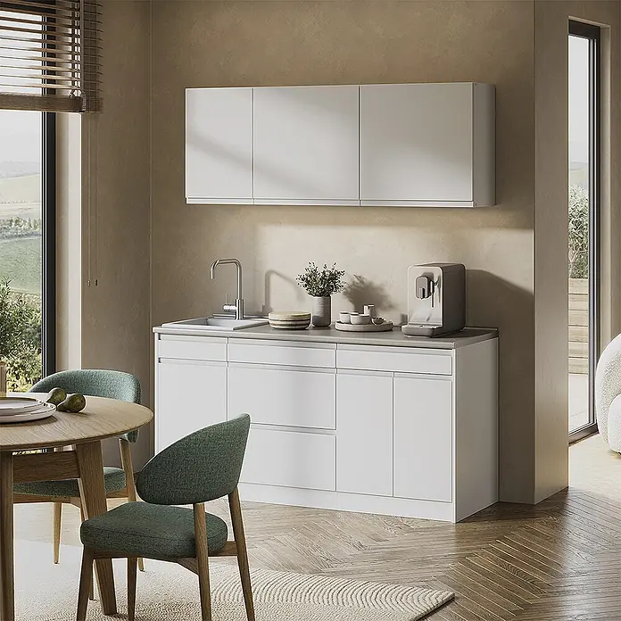 Singleküche R-Line 160 cm Weiß Art.-Nr. 70567 -  - Moderne Küche mit weißen Unter- und Oberschränken, integrierter Spüle und Kaffeemaschine. Im Vordergrund ein Holztisch mit grünen Stühlen.