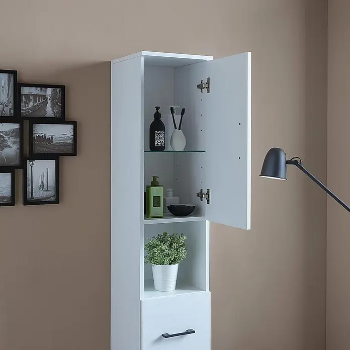 KV Badezimmerschrank hoch, weiß Export, reversibel mit Türen, Schublade und -  - Hoher weißer Badezimmerschrank mit offener Tür, der Regale mit Toilettenartikeln, eine Pflanze und eine untere Schublade zeigt, an einer beigen Wand.