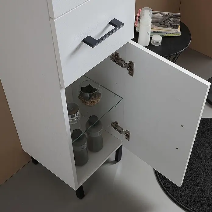 KV Halbhoher Badschrank weiß Export mit Türen und Schublade | Rimini -  - Hoher weißer Badschrank mit offener Tür, schwarzem Griff und Glasboden für Flaschen.