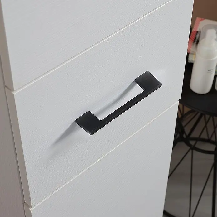 KV Halbhoher Badschrank weiß Export mit Türen und Schublade | Rimini -  - Ein moderner schwarzer Griff an einer weißen Schublade mit Holzmaserung eines Schranks.