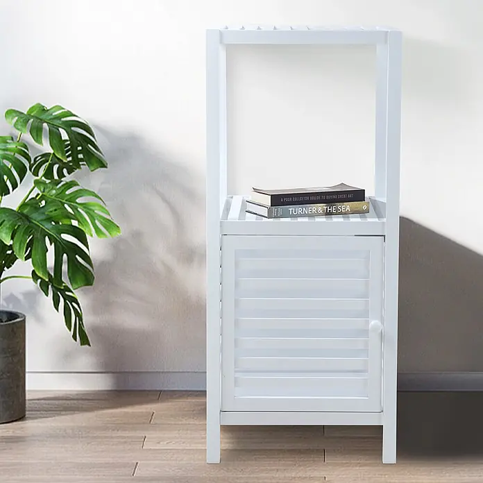 SVITA Badregal S Natur Bambus Weiß -  - Weißer Holzschrank mit Lamellentür und offenem Regal, Bücher haltend, in einem Raum mit Pflanze.