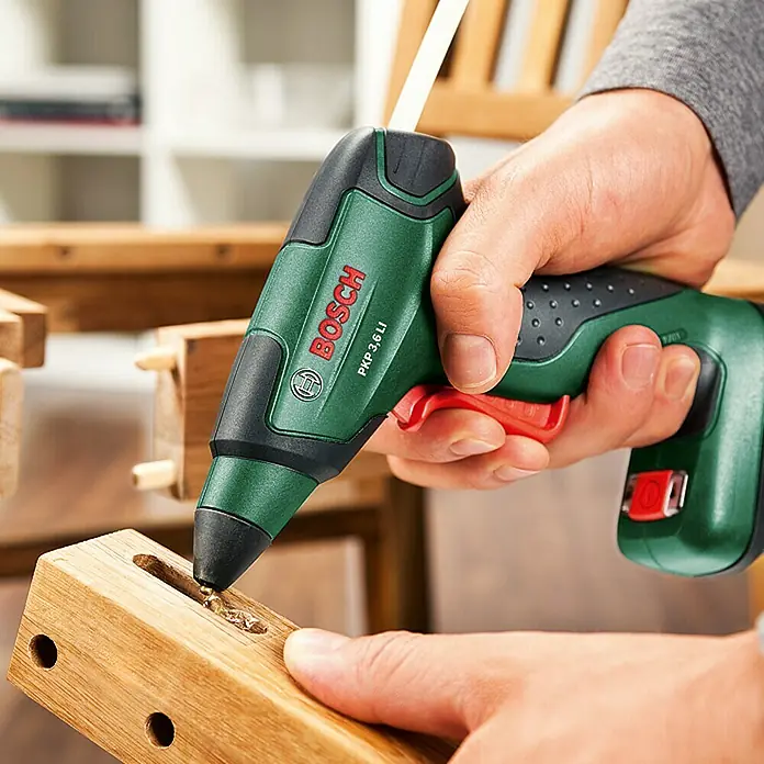 Bosch Pistola termoadhesiva de batería PKP 3,6 LI - 3,6 V, Iones de litio, 1,5 Ah, Diámetro cartucho de cola: 7 mm - Primer plano de una pistola de pegamento inalámbrica Bosch PKP 3,6 LI que se utiliza para pegar madera.