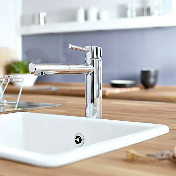 Grohe Concetto Spültischarmatur - Chrom, Glänzend, Ausziehbar - Nahaufnahme eines modernen Chrom-Wasserhahns an einem weißen Spülbecken, der das elegante Design und die Funktionalität des Wasserhahns hervorhebt.