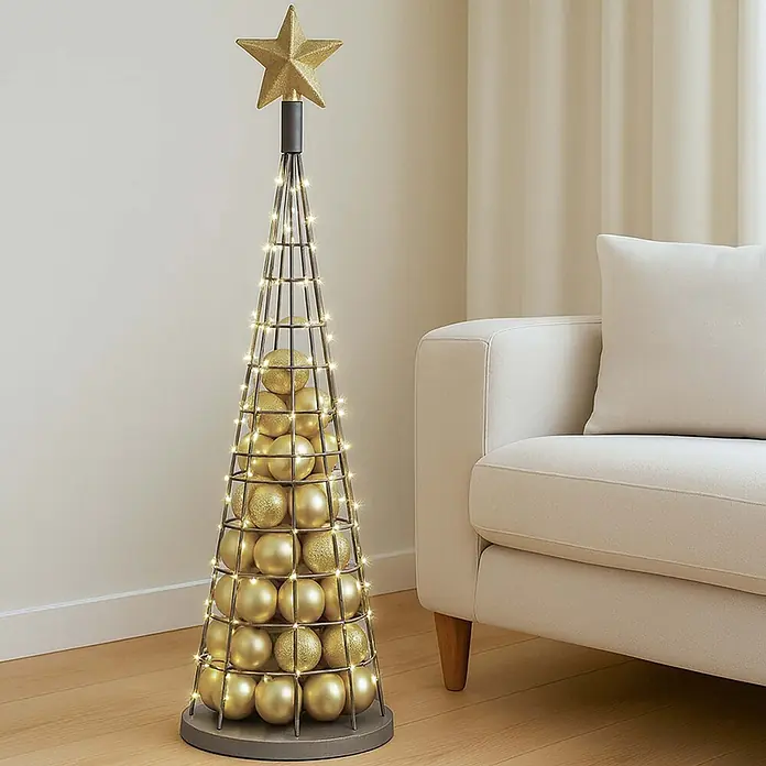 Mendler Deko-Weihnachtsbaum HWC-O91 Metall 115cm - silberfarben -  - Moderner Weihnachtsbaum aus dunklem Metall, gefüllt mit goldenen Kugeln und Lichterkette, gekrönt von einem Stern, neben einem cremefarbenen Sofa.
