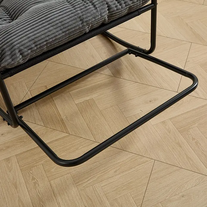 SONNENH Garten-Schaukelstuhl mit Cordpolster, Grau/Schwarz -  - Nahaufnahme eines grauen Kordkissens auf einem Stuhl mit schwarzem Metallgestell auf hellem Holzfußboden.