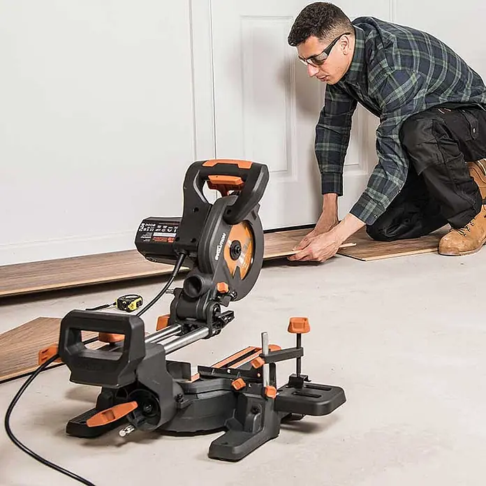 Evolution R185SMS+ Zug-Kapp- und Gehrungssäge 185 mm, TCT-Blatt -  - Schwarze und orange Gehrungssäge auf dem Boden, zum Schneiden von Holzbrettern für die Bodenverlegung verwendet.