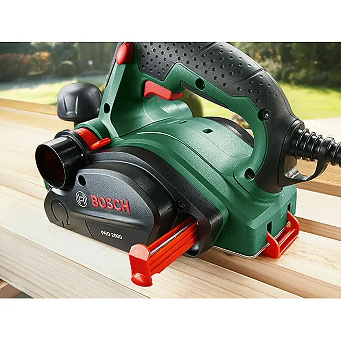 Bosch Elektrohobel PHO 2000 - 680 W, Hobeltiefe: 0 mm - 2 mm - Nahaufnahme des Bosch PHO 2000 Elektrohobels auf Holz, der ein präzises und sauberes Hobeln ermöglicht.