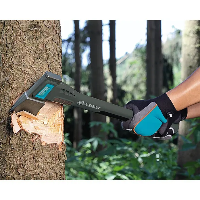 Gardena Universalaxt 1400 A - Länge: 60 cm - Nahaufnahme einer Gardena Axt, die in einem Baum steckt und Holz spaltet, während sie von Händen mit Handschuhen gehalten wird.