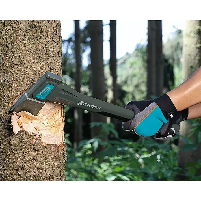 Gardena Universalaxt 1400 A - Länge: 60 cm - Nahaufnahme einer Gardena Axt, die in einem Baum steckt und Holz spaltet, während sie von Händen mit Handschuhen gehalten wird.