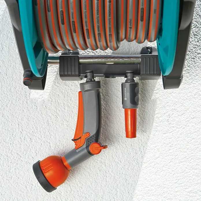 Gardena Classic Wandschlauchtrommel 50 Set - Schlauchlänge: 20 m - Eine Gardena Schlauchbox mit Schlauch und Spritze an einer weißen Wand.