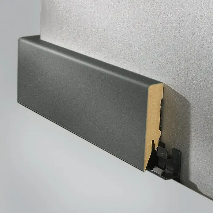 LOGOCLIC Sockelleiste Anthrazit - 260 cm x 80 mm x 18 mm, MDF - Detailaufnahme einer anthrazitfarbenen Fußleiste, die an einer Wand befestigt ist und ein modernes, minimalistisches Design zeigt.