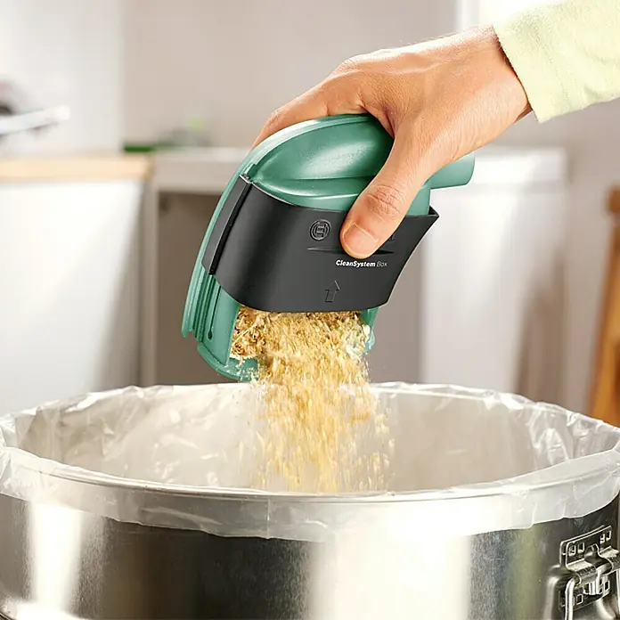 Bosch Handkreissäge PKS 55 A - 1.200 W, 5.600 U/min - Ein Mann entleert einen Bosch CleanSystem Box Staubbehälter in einen Mülleimer.
