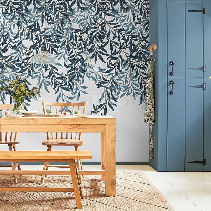 William Morris At Home Fototapete Willow Bough - Blau - Tapete mit blau-grünem Weidenblattmuster schmückt eine Esszimmerwand.