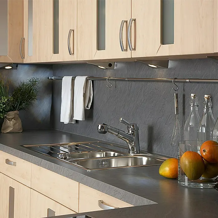 Resopal Basic Küchenarbeitsplatte nach Maß - Tagus Slate, Stärke: 3,8 cm, Breite: 60 cm - Küchenspüle mit Armatur, Abtropffläche und zwei Becken, eingebaut in eine moderne Arbeitsplatte mit hellem Holzunterschrank. Blickfang sind die frischen Mangos.
