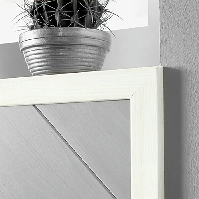 LOGOCLIC Winkelleiste Birnbaum Weiß - 260 cm x 22 mm x 42 mm, MDF - Nahaufnahme eines Dekoelements mit einem Kaktus in einem silbernen Topf auf einem weiß gerahmten, grauen Holzhintergrund.