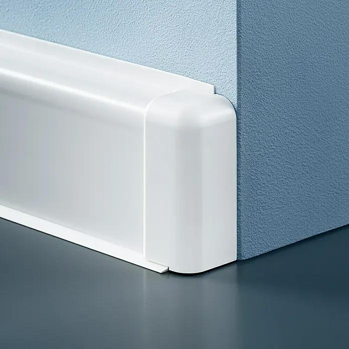 Sockelleistenkanal - 2 m x 50 mm x 20 mm, Reinweiß - Nahaufnahme einer weißen Fußleiste mit einer abgerundeten Ecke, die an einer blau gestrichenen Wand befestigt ist.