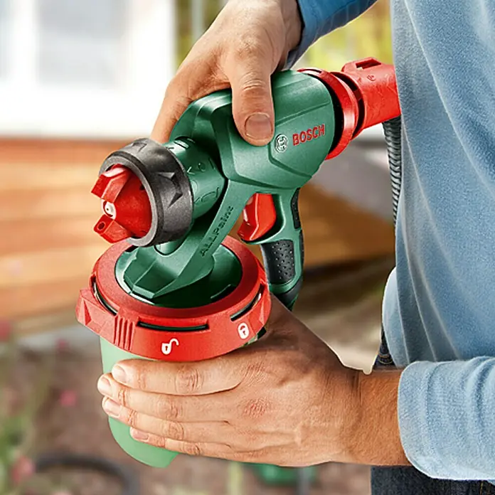 Bosch Farbsprühsystem PFS 3000-2 - Geeignet für: Alle Farbarten, Nennaufnahme: 650 W, 1.000 ml - Nahaufnahme einer Bosch ALLPaint Farbspritzpistole in den Händen, die die innovative Technologie für gleichmäßiges Auftragen hervorhebt.