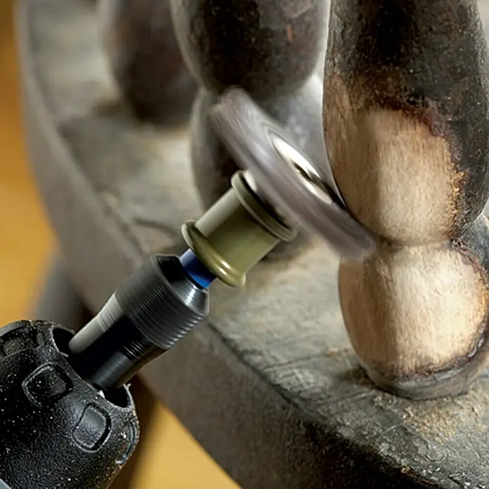 Dremel EZ SpeedClic Feinschleifbürste Mod. 473 S25 mm, Körnung: 220, Passend für: Dremel EZ SpeedClic Aufspanndorn Mod. SC 402 - Detailaufnahme einer rotierenden Bürste an einem Werkzeug, die ein Holzstück bearbeitet. Das Werkzeug entfernt die alte Farbe vom Holzstück.
