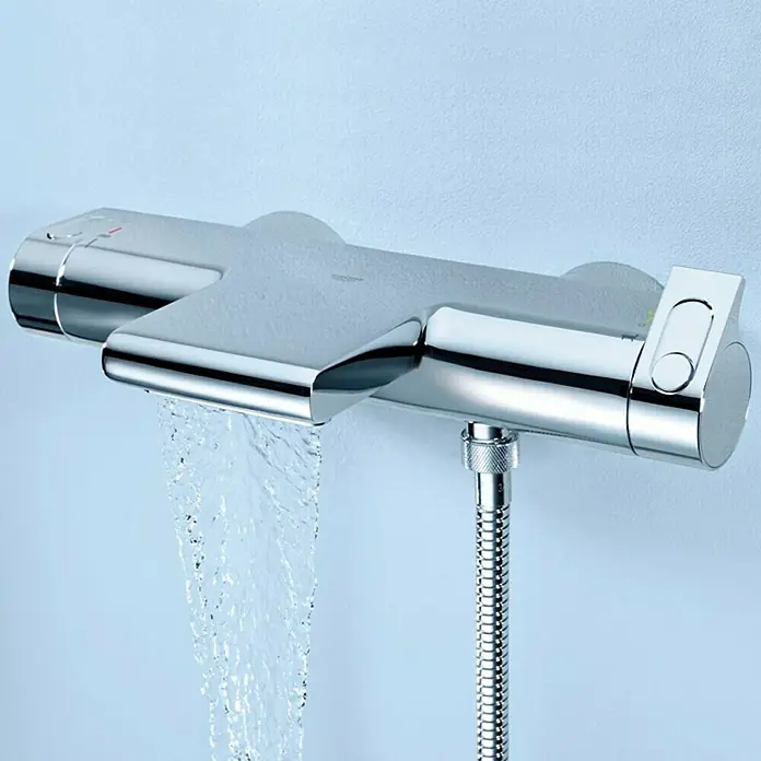 Grohe Grohtherm 2000 Wannenthermostat - Chrom - Eine Chrom-Brausearmatur ist an einer hellblauen Wand angebracht, aus der Wasser fließt, und ein Brauseschlauch ist angeschlossen.