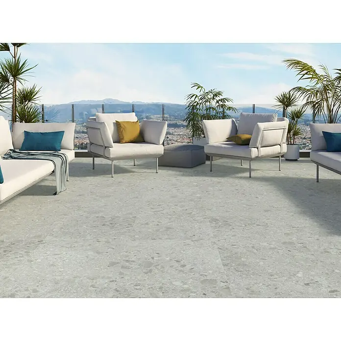 Feinsteinzeugfliese Hannover Steel - 60 x 60 cm, Grau, Matt - Terrassenmöbel-Set mit zwei Sesseln, zwei Sofas, einem Hocker und vielen Pflanzen auf dem Dachgarten mit Terrazzoboden.