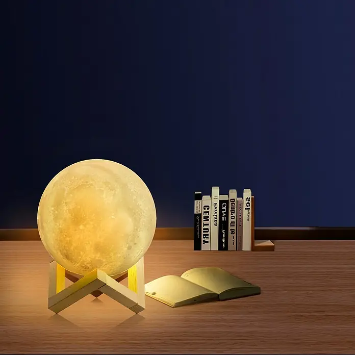 Voltomat Tischleuchte Luna - 15 W, Weiß, RGB - Mondlampe auf einem Holztisch mit Büchern, die eine gemütliche und fantastische Atmosphäre erzeugt.