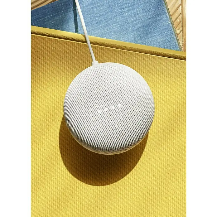Google Nest Starter-Set Ledvance Smart+ BT Leuchtmittel - Kreide, 5,5 W, E27, Warmweiß, Dimmbar - Nahaufnahme eines Google Nest Mini Smart Speakers in Weiß, der auf einem gelben Buch liegt, mit einem blauen Buch im Hintergrund.