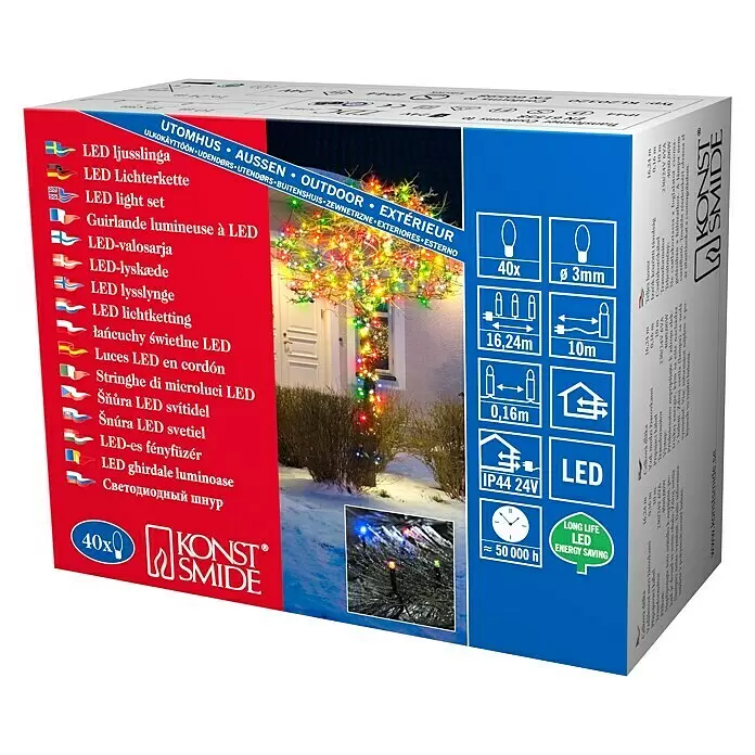 Konstsmide LED-Lichterkette Micro LED - Außen, Lichtfarbe: Mehrfarbig, Anzahl Leuchtmittel: 40 Stk., Netzbetrieben - Mehrfarbige LED-Lichterkette für den Außenbereich, schmückt einen Winterbusch und Baum vor einem Haus.