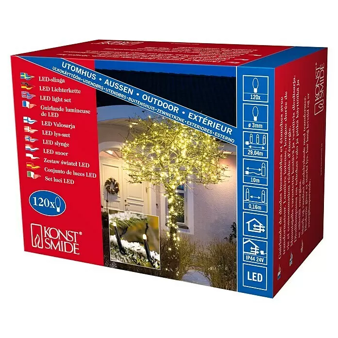 Konstsmide LED-Lichterkette Micro LED - Außen, Lichtfarbe: Warmweiß, Anzahl Leuchtmittel: 120 Stk., Netzbetrieben - Produktverpackung mit warmweißen LED-Lichterketten, die einen Baum im Freien vor einem Haus festlich beleuchten.