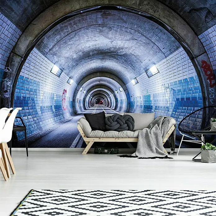 Fototapete Tunnel IIIB x H: 312 x 219 cm, Vlies - Ein stilvolles Wohnzimmer mit Tunnel-Wandbild, ergänzt durch ein Futon, einen Teppich mit geometrischem Muster und Akzentmöbel.