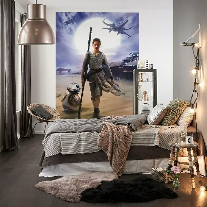Komar Star Wars Fototapete Rey - 4 -tlg., B x H: 184 x 254 cm, Papier - Schlafzimmer mit einem Star Wars Wandbild mit Rey, BB-8 und Raumschiffen, Bett mit Überwurf und Kissen, Sessel und Lampe.
