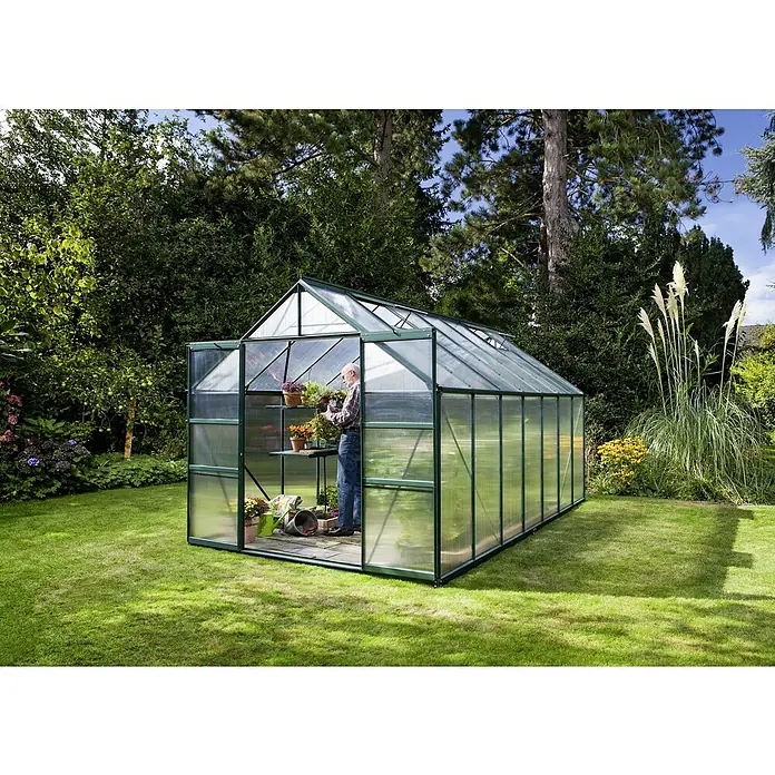 Vitavia Gewächshaus Mars 11500 Plus - Außenmaß inkl. Dachüberstand (B x T): 257 x 445 cm, 6 mm, Smaragd - Ein geräumiges Gewächshaus im Garten, ausgestattet mit Regalen und einem Gärtner, ideal für Hobbygärtner, die Pflanzen ziehen möchten.