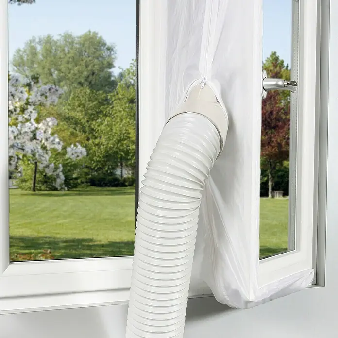 Voltomat Fensterabdichtung Hot Air Stop - Weiß, Breite: 40 cm - Weißer Fensterabdichtung Stoff mit einem weißen Schlauch einer mobilen Klimaanlage vor einem Fenster mit Blick ins Grüne.