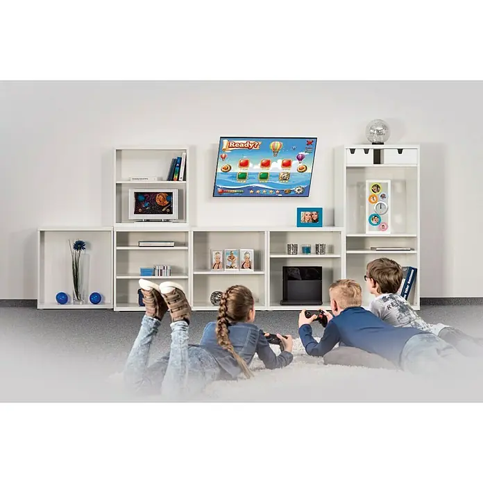 Soporte para televisor - Televisores 37 - 75 pulgadas, 60 kg - Niños jugando videojuegos en un sofá blanco frente a una estantería blanca con decoración, incluyendo una televisión y fotos enmarcadas.