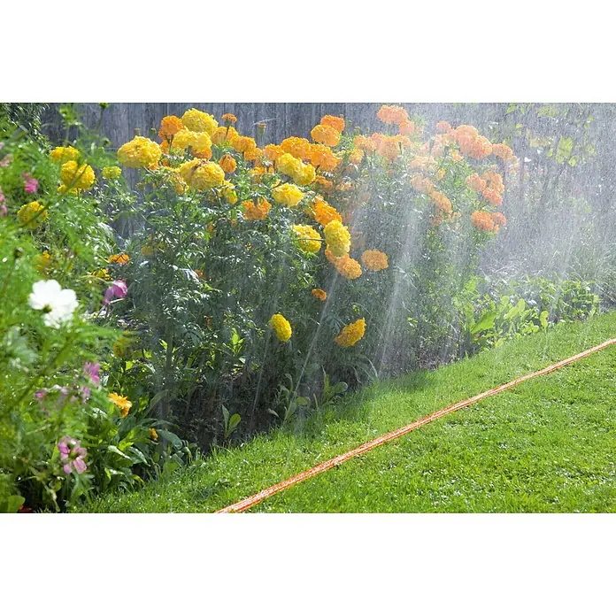 Gardena Schlauchregner - Länge: 7,5 m, Mit Wasserstopp - Bewässerung mit einem orangefarbenen Gartenschlauch, der auf einem saftig grünen Rasen liegt und Blumen bewässert.