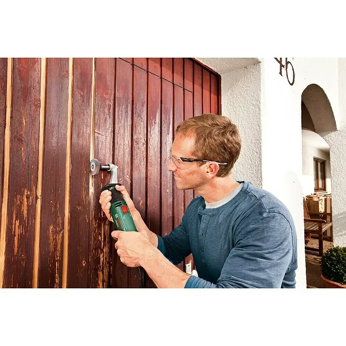 Bosch Lamellenschleifrolle - Körnung: 80, Breite: 10 mm - Mann benutzt ein Bosch Multifunktionswerkzeug zum Schleifen einer Holztür, wobei er Schutzbrille und Ohrstöpsel trägt, um sicher zu arbeiten.