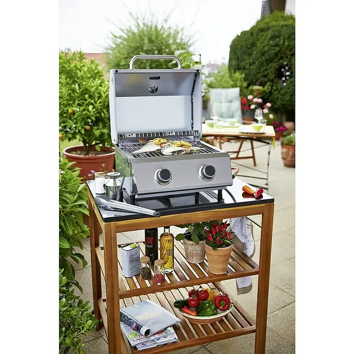 Sunfun Diana Rollwagen - 77 x 58 x 88 cm - Ein kompakter Grill auf einem Holztisch im Freien. Auf dem Grill liegt Fisch, der mit Zitrone garniert ist, umgeben von frischen Zutaten.