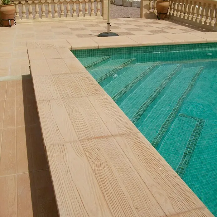 Pavimento Remate piscina Teka - 50 x 45 cm, Beige - Primer plano de una piscina con azulejos celestes y una cubierta de piscina de madera que crea un ambiente relajante.