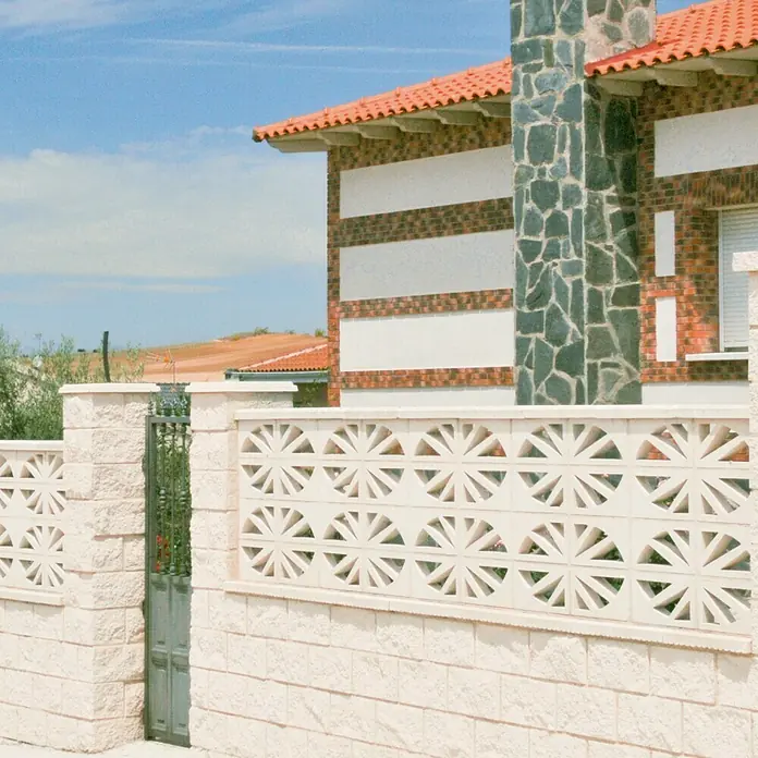 Celosía de pared Abanico - 40 x 20 cm, Blanco - Primer plano de una valla blanca decorativa con un patrón geométrico, que encierra una casa con techo de tejas rojas.