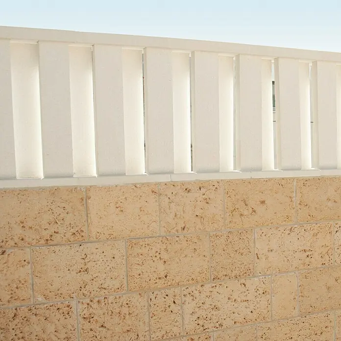 Cubremuros plano Liso - 50 x 27 x 4 cm, Blanco, Hormigón - Primer plano de una pared con ladrillos decorativos y una balaustrada calada blanca que añade un acento moderno.