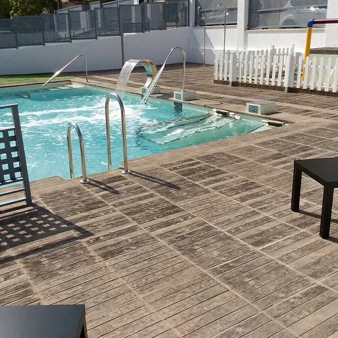 Pavimento para exterior Madera Nogal - 50 x 50 cm, Marrón - Acogedora zona de piscina con cascada, escalera y elegantes baldosas en el suelo. Las áreas de descanso ofrecen un lugar ideal para relajarse junto al agua.