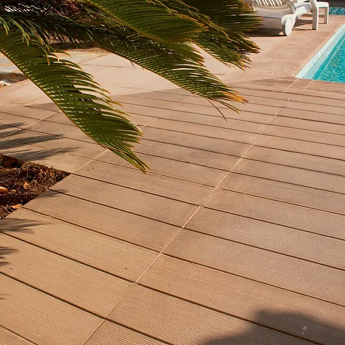 Pavimento para exterior Ipe Nogal - 57 x 44 cm, Marrón - Un primer plano de baldosas de composite para terraza, perfectas para una zona de piscina, que ofrecen un ambiente exterior relajante.