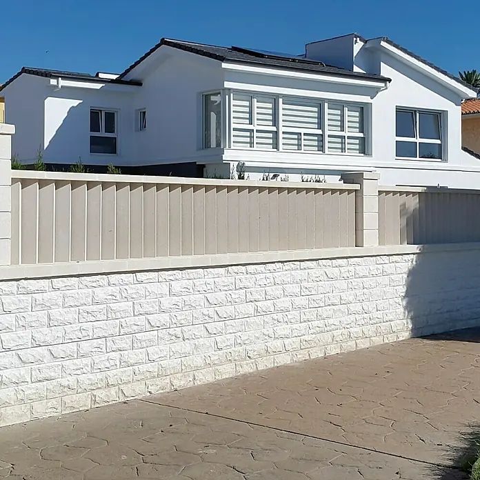 Cubremuros plano Liso - 50 x 27 x 4 cm, Blanco, Hormigón - Una fachada de casa moderna con una elegante pared de piedra y una valla de listones beige, que acentúa su diseño arquitectónico.