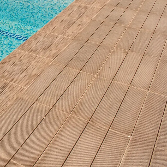Pavimento para exterior Ipe Nogal - 57 x 44 cm, Marrón - La imagen muestra una piscina con una terraza de madera. Las baldosas de madera dan a la zona de la piscina un aspecto moderno y elegante.