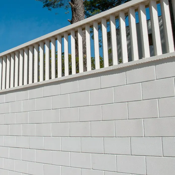 Tapa izquierda de protección contra viento - Hormigón polímero, Blanco - Una pared de ladrillos blanca con una barandilla blanca encima, posiblemente un límite de propiedad. La valla ofrece privacidad y seguridad.