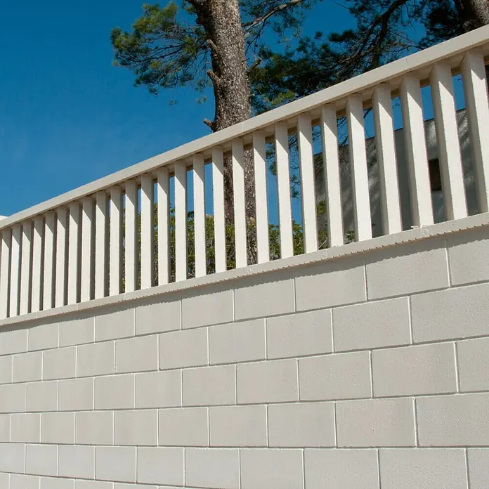 Cubremuros plano Liso - 50 x 27 x 4 cm, Blanco, Hormigón - Primer plano de una pared blanca decorativa con una valla de listones, sobre un cielo azul y un árbol.